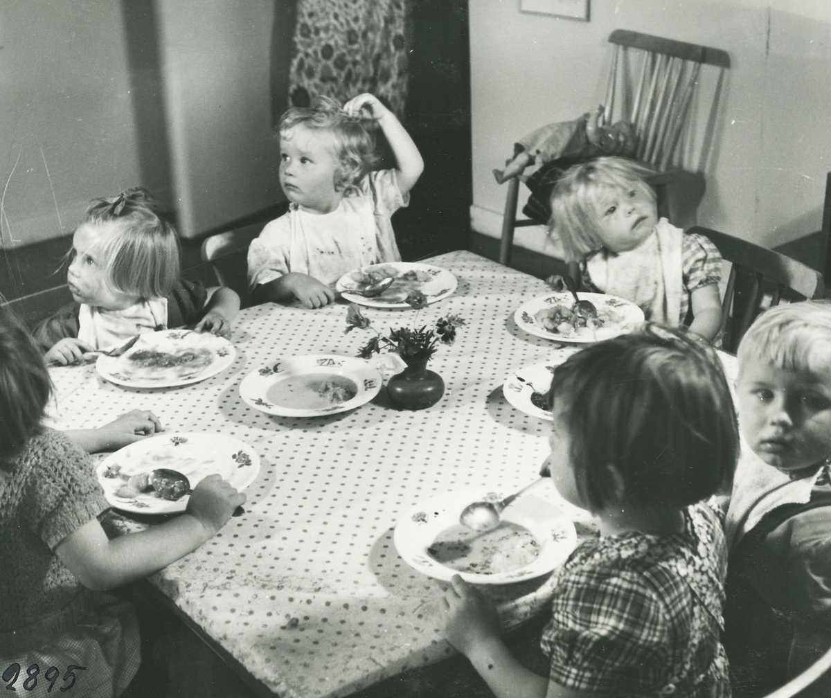 Interiörbild. Daghemmet Blomkulan. Pågående måltid.
Personer: Sex okända barn.