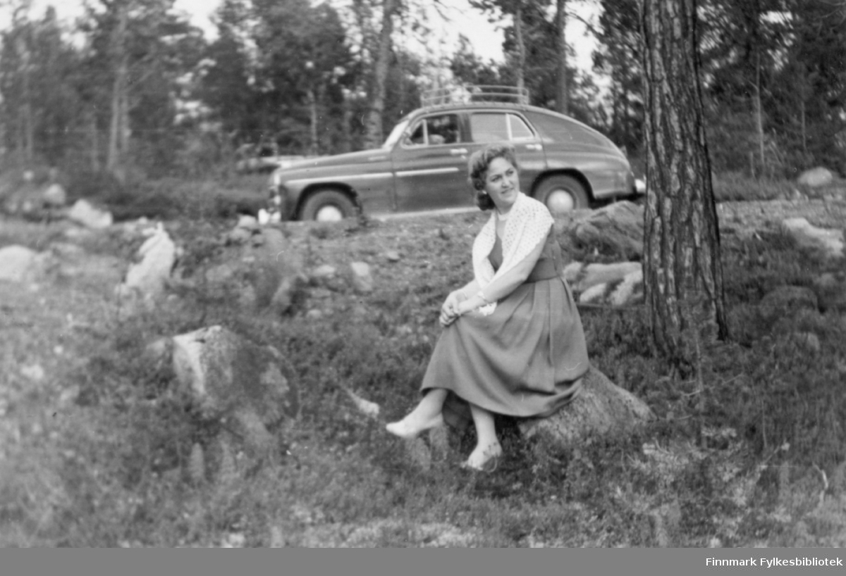 Ester fotografert i skogen på 1950-tallet. En bil, russisk Popeda eller tilsvarende polsk Warsawa (1954-1957) står i bakgrunnen. Familiealbum tilhørende familien Klemetsen. Utlånt av Trygve Klemetsen. Periode: 1930-1960.