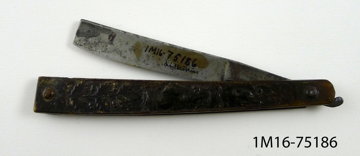 Rakkniv. Skaftet är tillverkat av horn med pressade figurer, däribland 2 mansbyster. Kniven är märkt WARRAW.