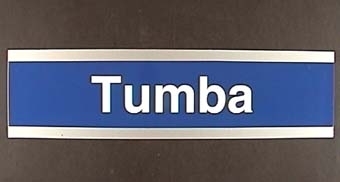 Långsmal skylt av plast med vit text på blå botten: "Tumba".