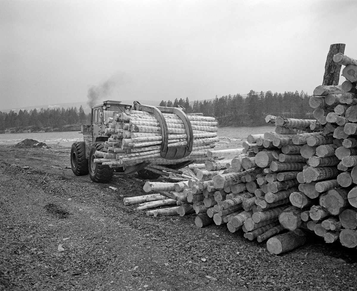 Utislag med hjullaster fra en terminalplass ved Sølenstua i Engerdal i Hedmark. Tømmeret ble hentet på elvebakken, der det var lagt opp i velter langs bredden av Femundselva (Trysilelva).  Med den digre, frontmonterte, hydrauliske kloa som arbeidsredskap hentet maskinføreren tømmerstokkene, som han deretter slapp ut i elva med sikte på at det skulle flyte videre med strømmen. Dette fotografiet ble tatt 22. mai 1986.  Tømmerterminalen på Røskjota ble bygd etter at Klarälvens Flottningsörening i 1953-54 bidro til at det ble bygd bilveger mellom Sølenstua og Galten, og opp til Femundsenden.  Dermed kunne tømmer fra Femund tas opp ved Gløta, og virke fra traktene rundt Isteren kunne hentes ved Isterfossen og kjøres til denne velteplassen, hvor stokkene ble lagt opp for tørking og fløting påfølgende år.  Fra 1965 og framover fikk Klarälvens Flottningsförening opparbeidet flere terminalplasser av den typen vi ser på dette fotografiet i Trysil og Engerdal.  Slike løsninger ble mulige etter at skogsbilvegnettet i de to kommunene var blitt såpass stort at man anså det for mulig å avvikle fløtinga i de minste sidevassdragene. Omlegginga skjedde i forståelse med Trysilvassdragets skogeierforening.  Terminalplassene hadde ikke bare hjullastere, men i mange tilfeller også barkemaskiner, noe som overflødiggjorde det manuelle arbeidet med barkespader, og dermed forenklet driftsprosessene på hogstfeltene vinterstid.

Under utislaget ved Femundselva i 1986 ble det brukt tre hjullastere som alle tilhørte maskinentreprenøren og rallyføreren Olle Arnesson fra Likenäs i Torsby kommune i Sverige.  Maskinførere var Pinnochio Carlson, Eber Halvardsson og Ove Jonsson.