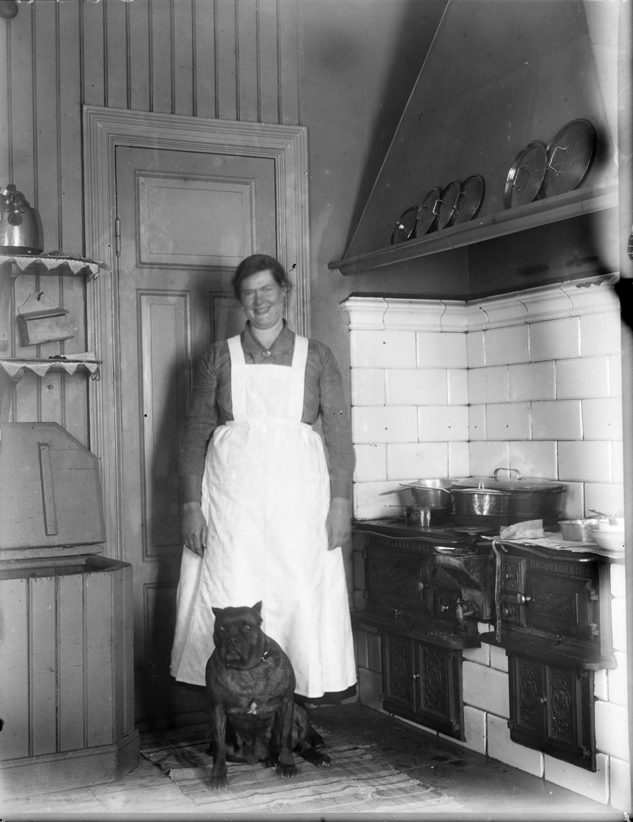 "Interiör från Eklunda gård, Lisa Holm i Köket, hunden fram", Simtuna socken, Uppland 1924