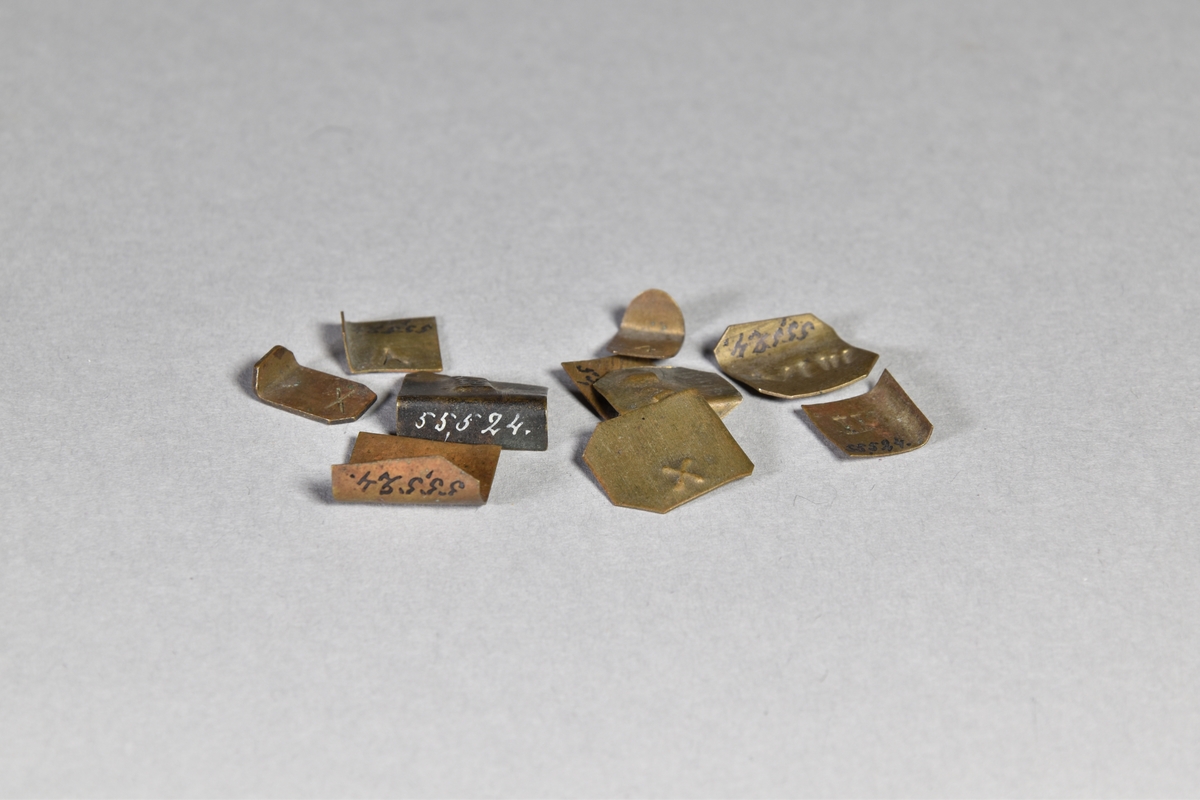 Vikter, 10 st, av tunn mässingsplåt i olika former med instämplade romerska siffror.