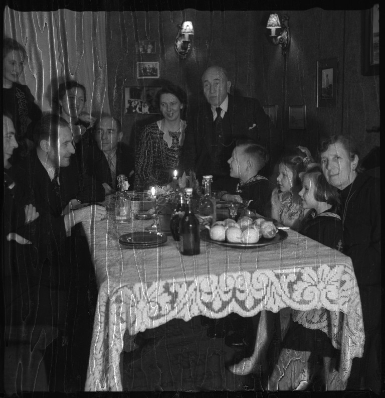 Familien Johannessen samlet for feiring av jul hos Einar Juvvik (født Johannessen). De sitter til bords og går rundt juletreet.