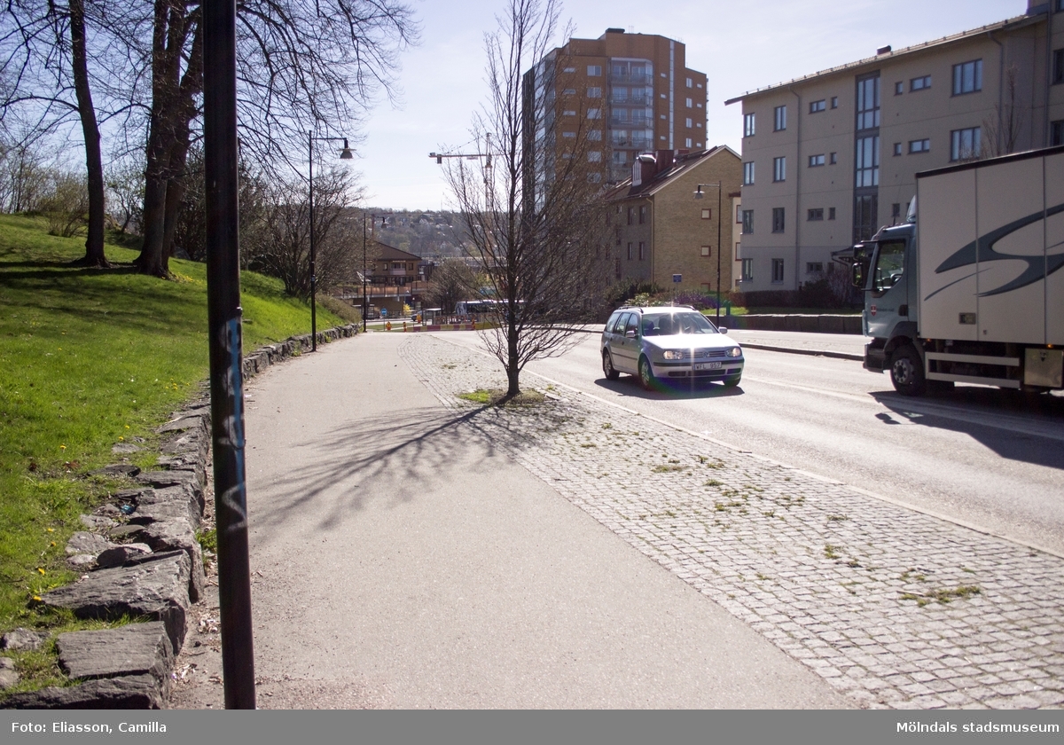 Vy österut mot höghuset på Storgatan 32A, Ulla Jacobssons Plats och Mölndalsbro, år 2015. Till vänster ses gräsmattan nedanför Fässbergs kyrka. Till höger området Björkåsen 3. Dokumentation av platsen innan rivning och nybyggnation.