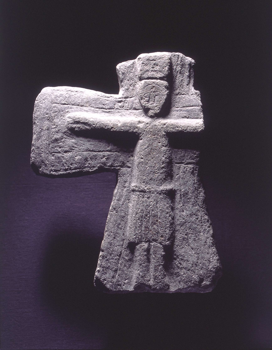 Kors hugget ut av én stein. På framsiden av korset er et relieff av Jesus, med krone på hodet. Høyre arm og øverste stav har knekt av steinen.