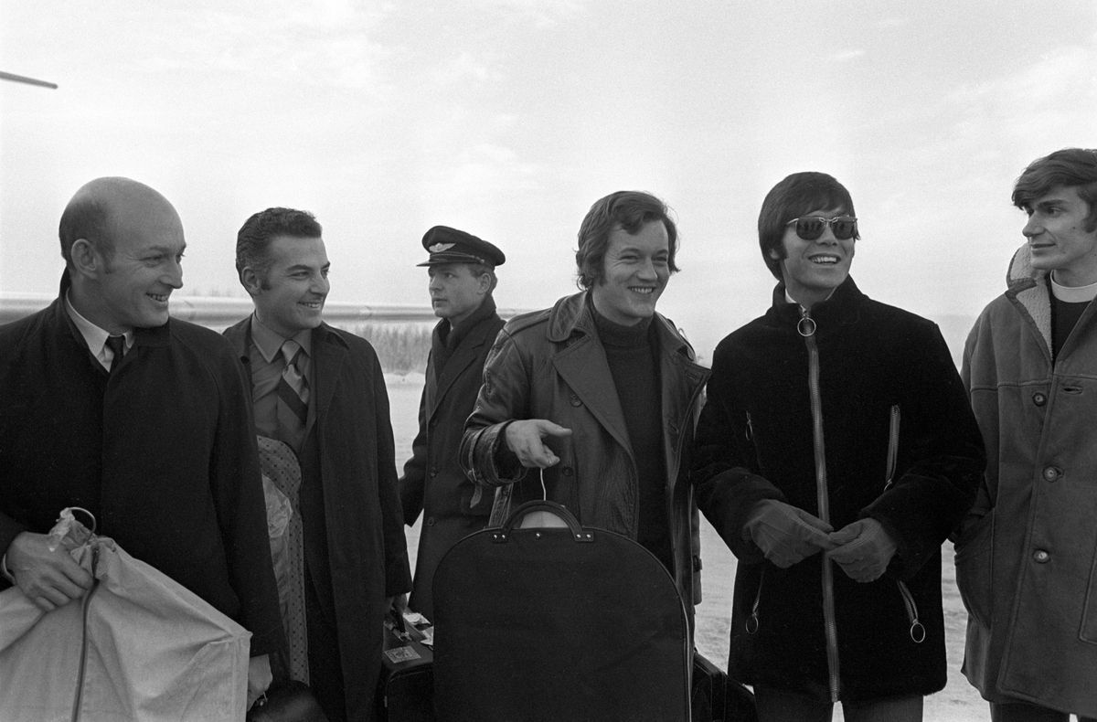 Popsanger Cliff Richard ankommer Fornebu på vei til konsert i Bergen. Cliff nr. to fra høyre sammen med The Shadow's trommeslager Brian Bennett til venstre. To ukjente personer helt til venstre.