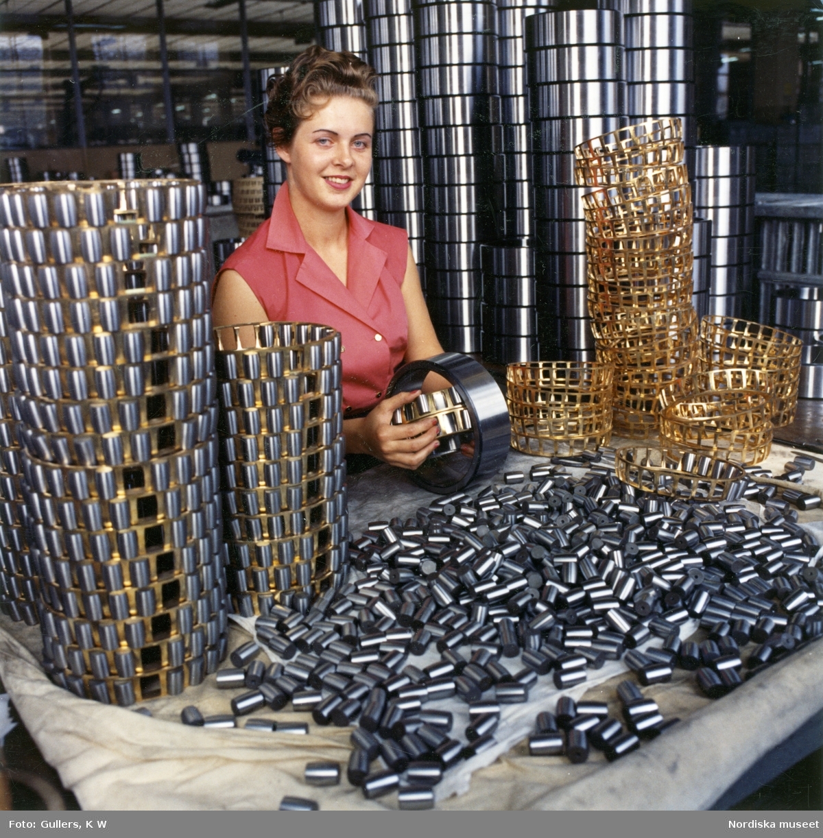 Interiör från SKF:s kullagerfabrik i Göteborg. Kvinna monterar ihop delar till kullager.