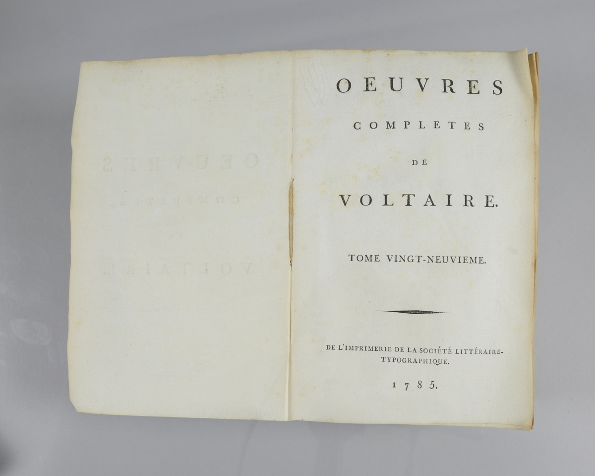 Bok, pappband,"Oeuvres completes de Voltaire", del 29, tryckt 1785.
Pärmen klädd med gråblått papper, skurna snitt. På ryggen klistrad pappersetikett med tryckt text samt volymens nummer. Ryggen blekt.