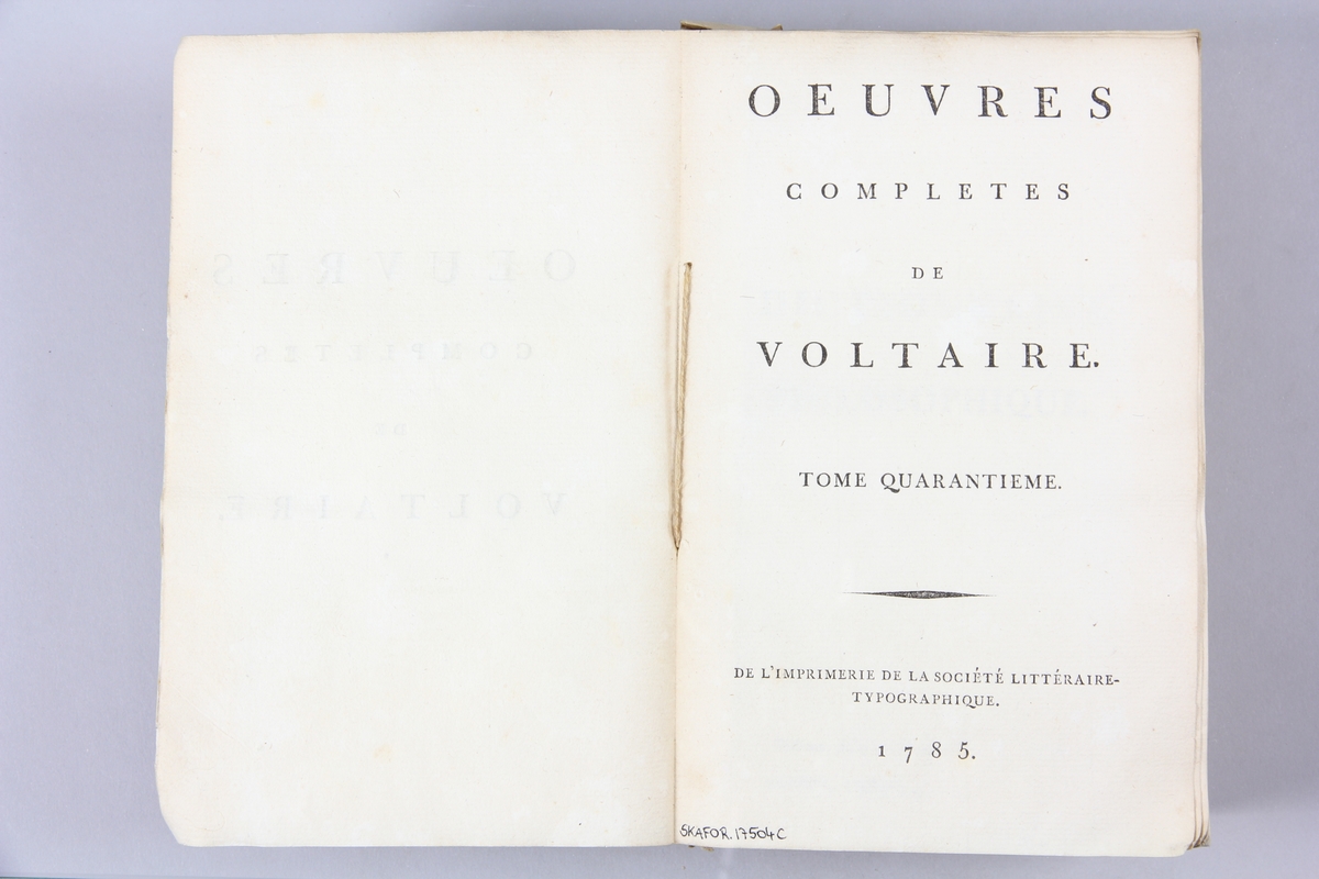 Bok, pappband,"Oeuvres complètes de Voltaire." del 40, tryckt 1785.
Pärm av gråblått papper, skurna snitt. På ryggen pappersetikett med tryckt text med volymens namn och nummer. Ryggen blekt.