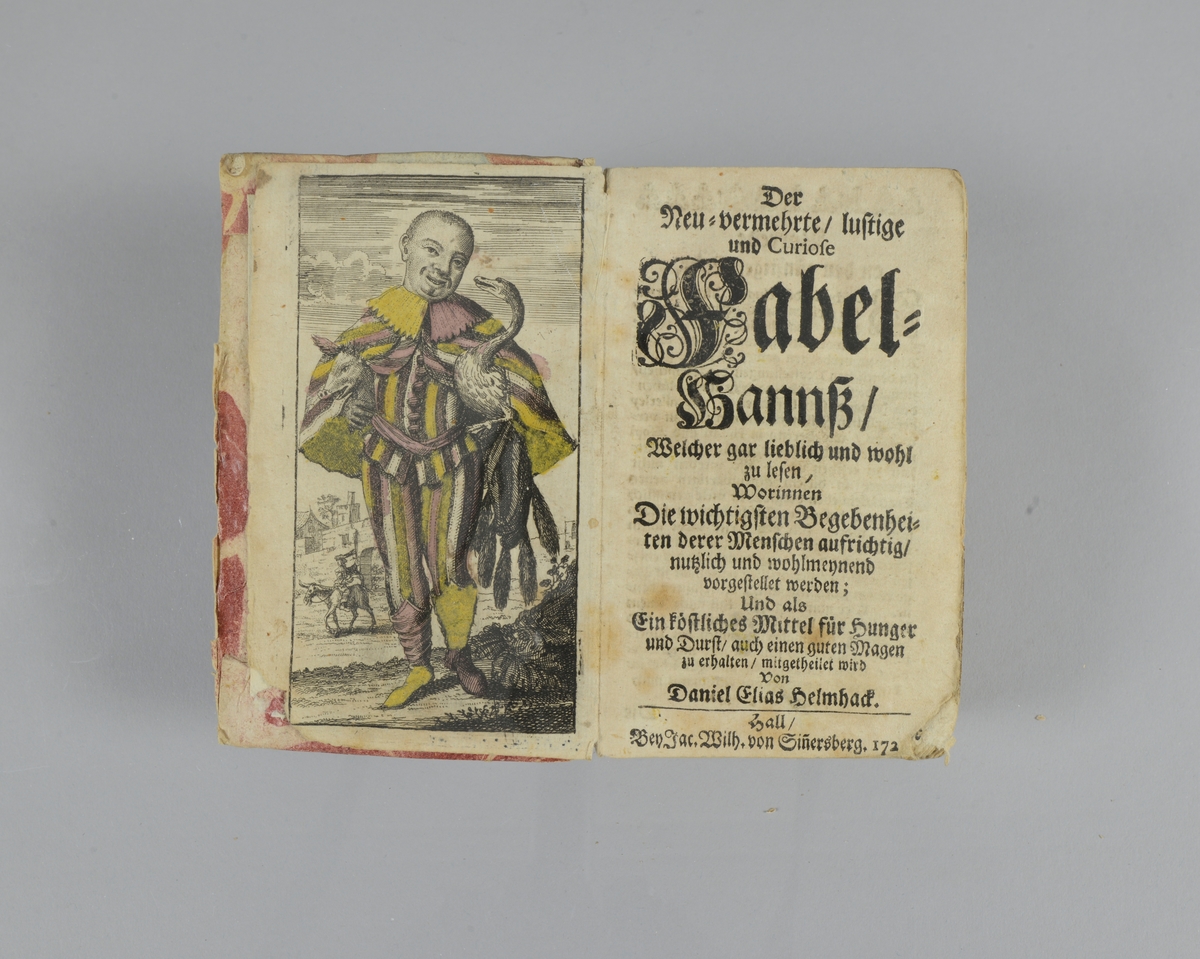 Bok, pappband, "Der neu-vermehrte/lustige und curiose Fabel-Hanns ", tryckt 1720 i Halle. Håda pärmar klädda med marmorerat papper, blekt rygg med etikett med bokens titel och nummer. Skuret snitt. Med färglagt kopparstick.