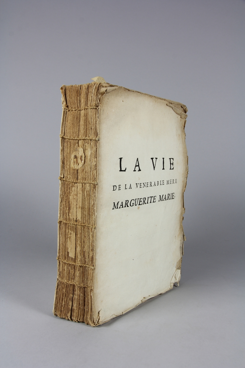 Bok, häftad, "La vie de la vénérable mère Marguerite Marie". Pärmar av marmorerat papper, oskuret snitt, skadad rygg. Anteckning om inköp.