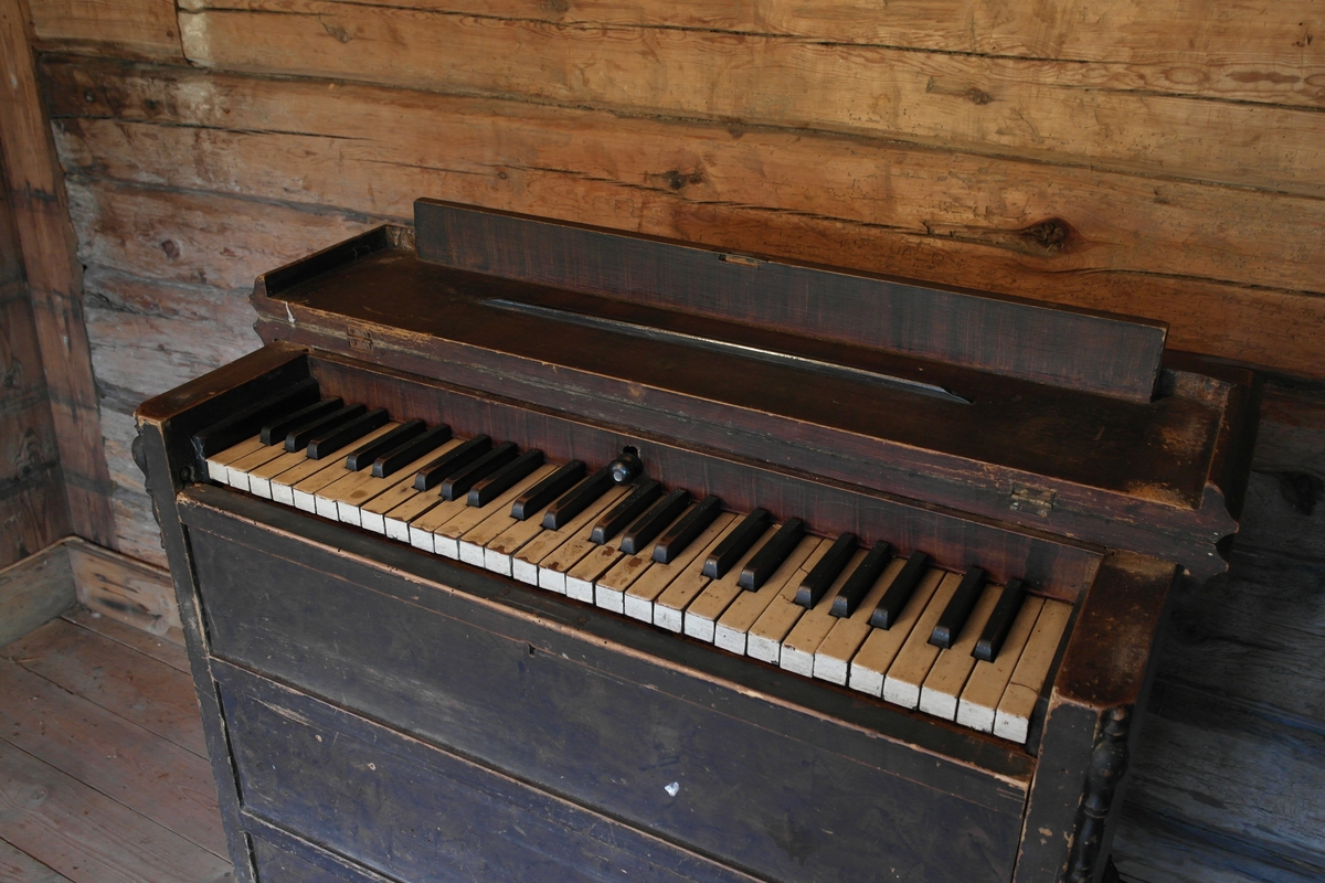 Husorgel i høvlet, pusset og brunmalt furu, samt smidd jern. Orgelet har et lokk over tastaturet som er til å slå opp. Det har avfasede hjørner i fronten og skåret dekor. Det er en buet åpning ved pedalen.