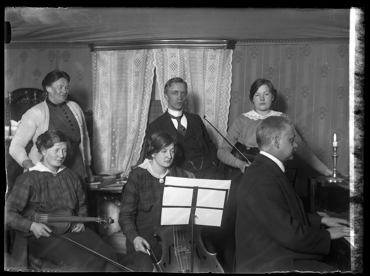 Anna (troligen Glasin), "Lalle", Eva, Anna & Edith Claesson och far (troligen fotografen Harald Olssons far Axel Teodor Olsson) spelar fiol, cello och piano.