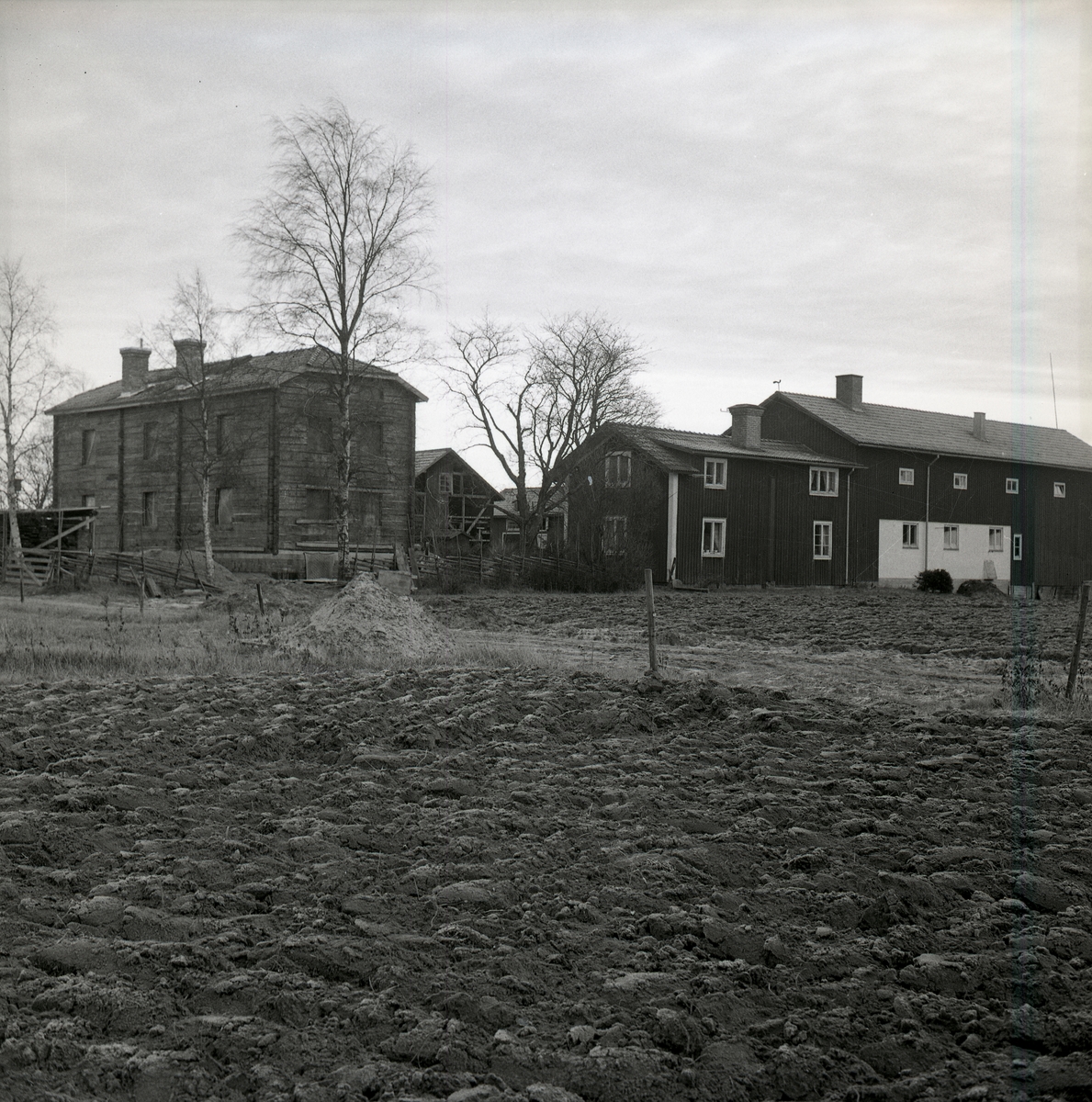 En gård med många byggnader bakom plöjd åkermark den 19 november 1967.