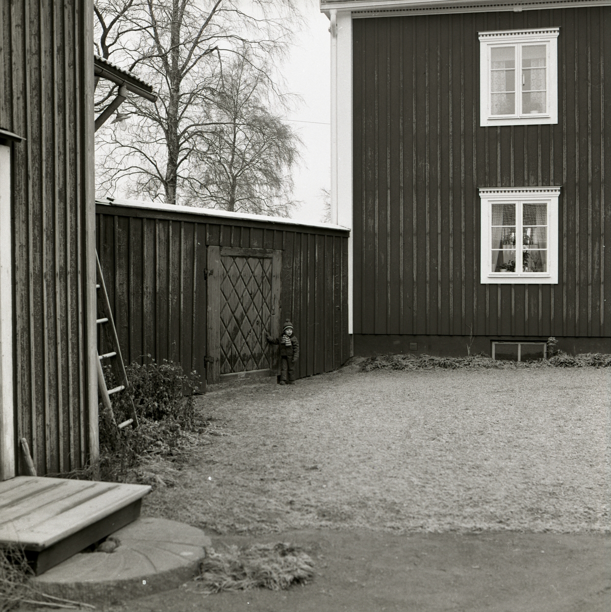 En pojke står framför en port i ett plank vid gården Sunnanåker, 1972.