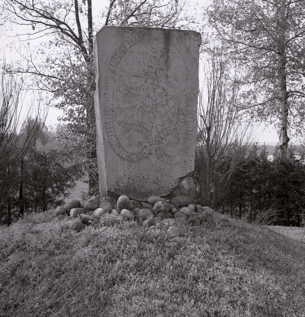 En runsten på en kulle vid Gripsholm i Mariefred. Vid runstenens fot ligger en samling mindre stenar.