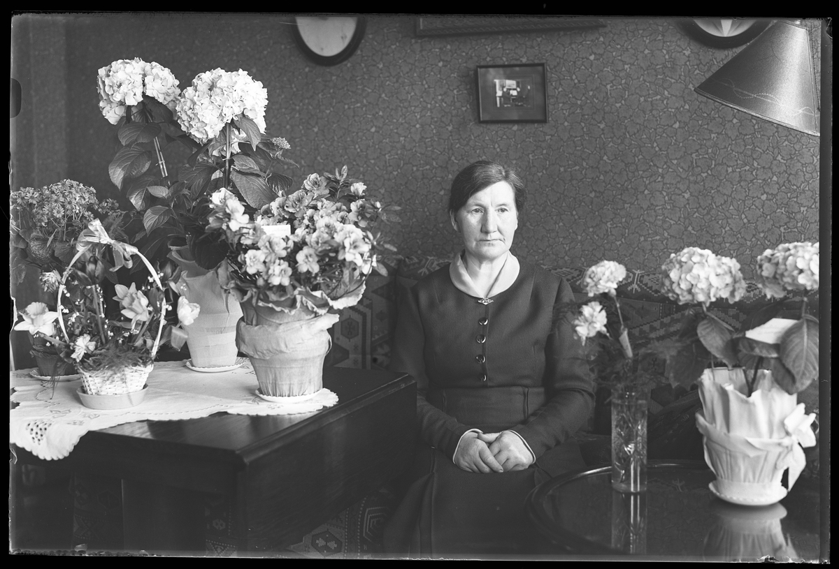 Emma Sofia Johansson (fotografens mamma) fotograferad omgiven av blommor på sin 60årsdag.