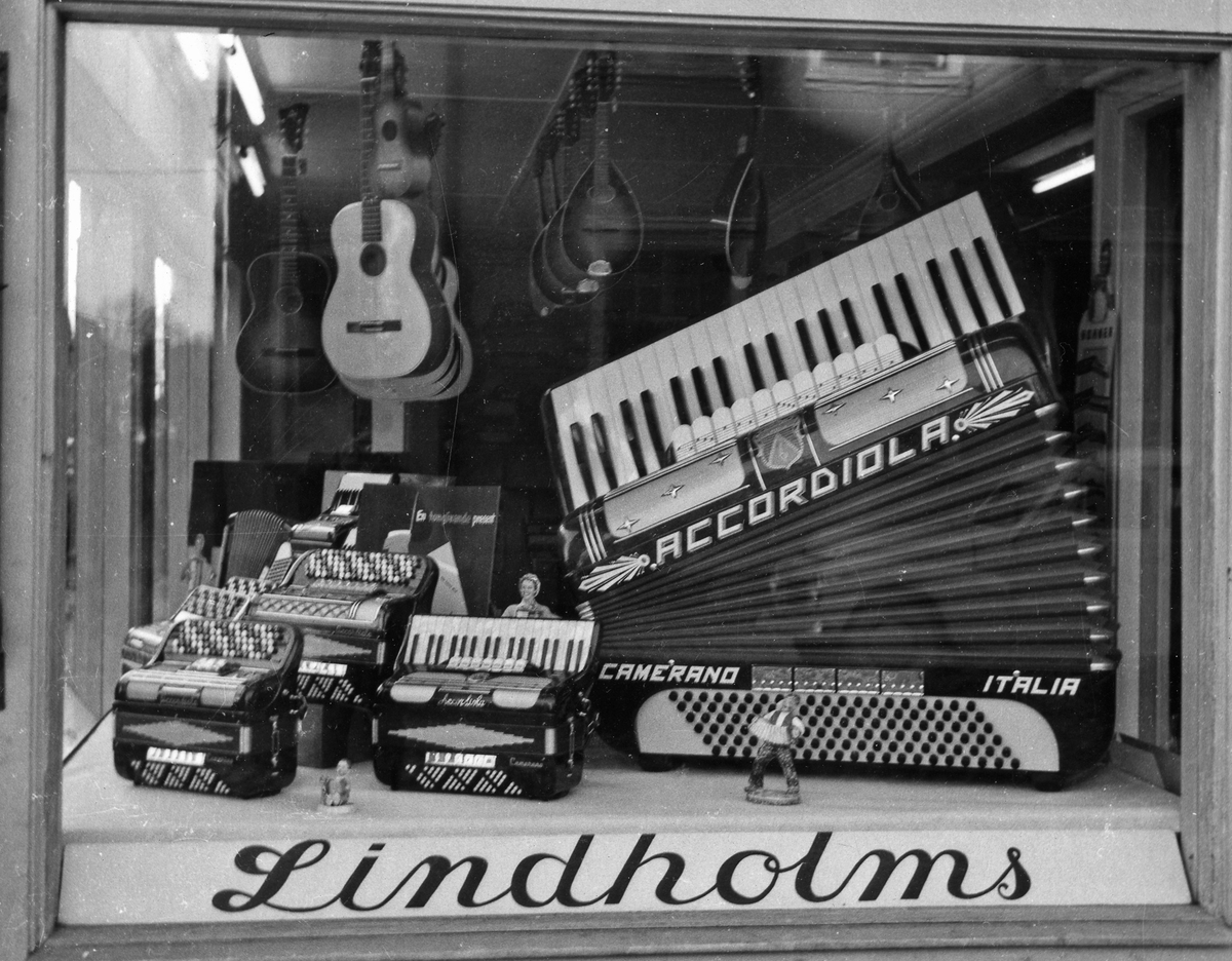 Bild på skyltfönster, i fönstret finns ett flertal dragspel och i taket hänger gitarrer och mandoliner.
Lindholms Musikaffär.
Kvarteret Storken 5. Norra Strömgatan.