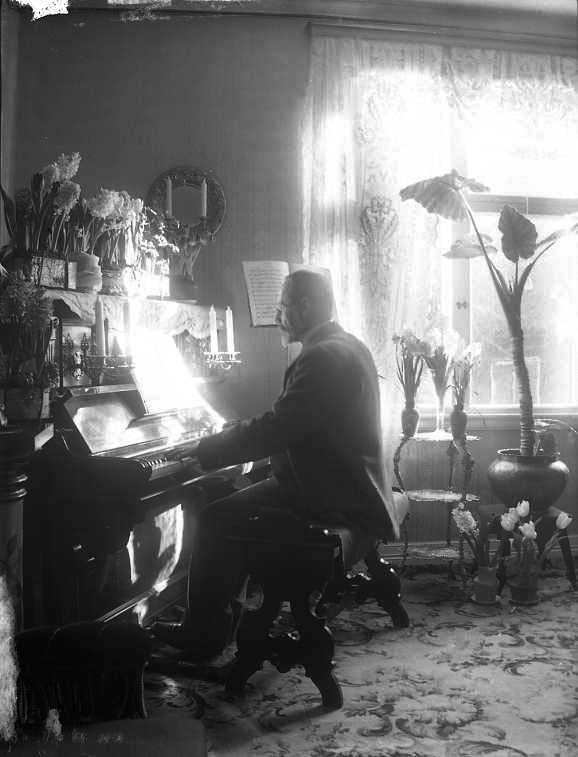Doktor Werner spelar pianot på Brahegatan 20. Solljuset strilar in från ett fönster till höger.