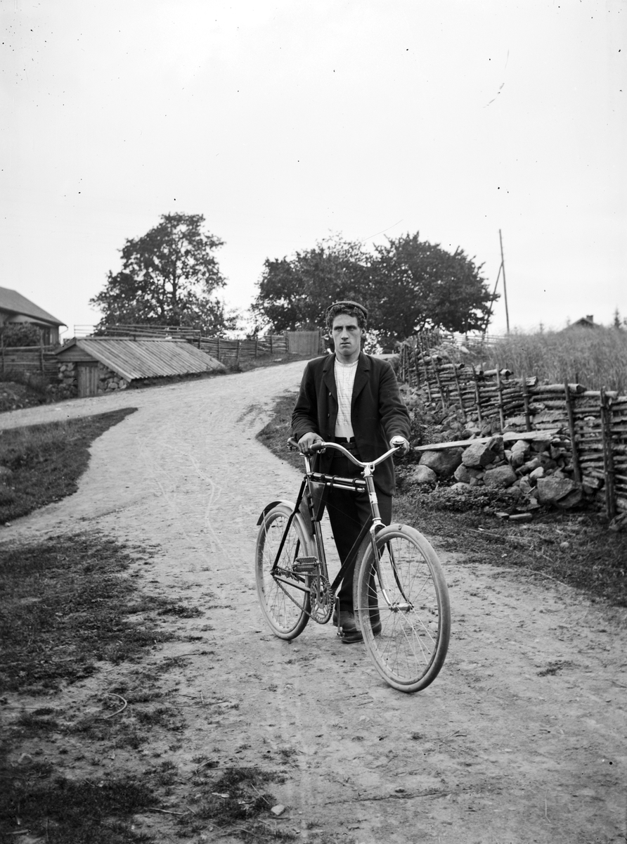 En man med sin cykel på en väg i Ökna socken, Vetlanda.