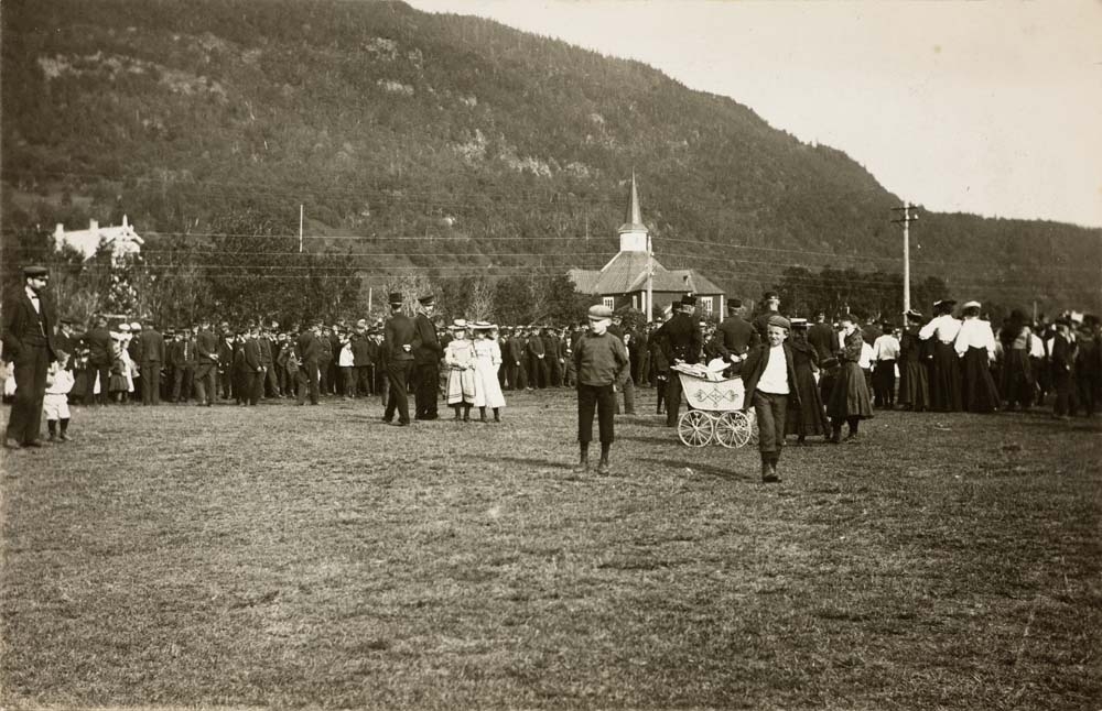 Postkort med mye folk, både voksne, barn og soldater, samlet nedenfor Dolstad kirke, Vefsn. Ukjent årstall.