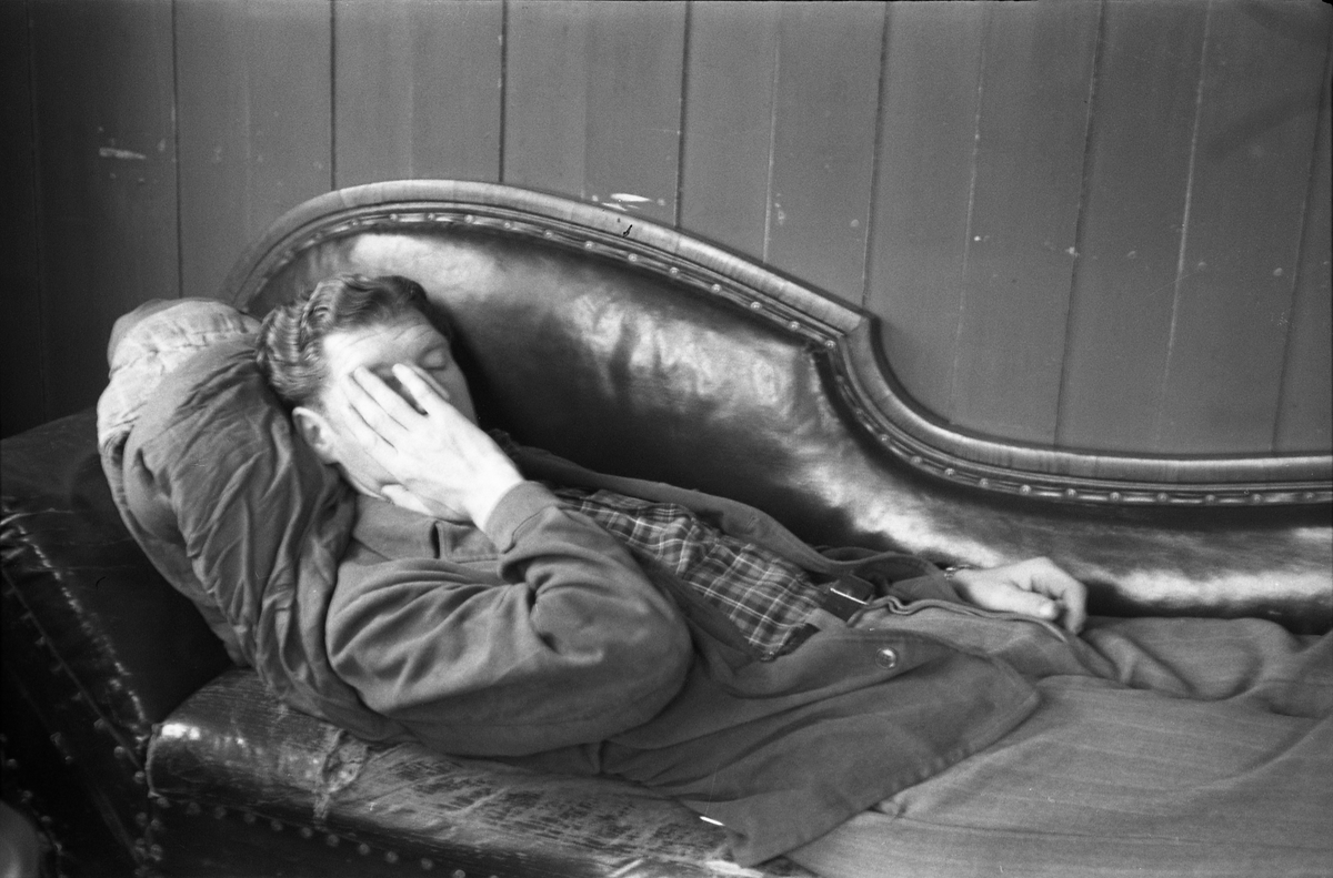 En uidentifisert mann som hviler på en sjeselong.