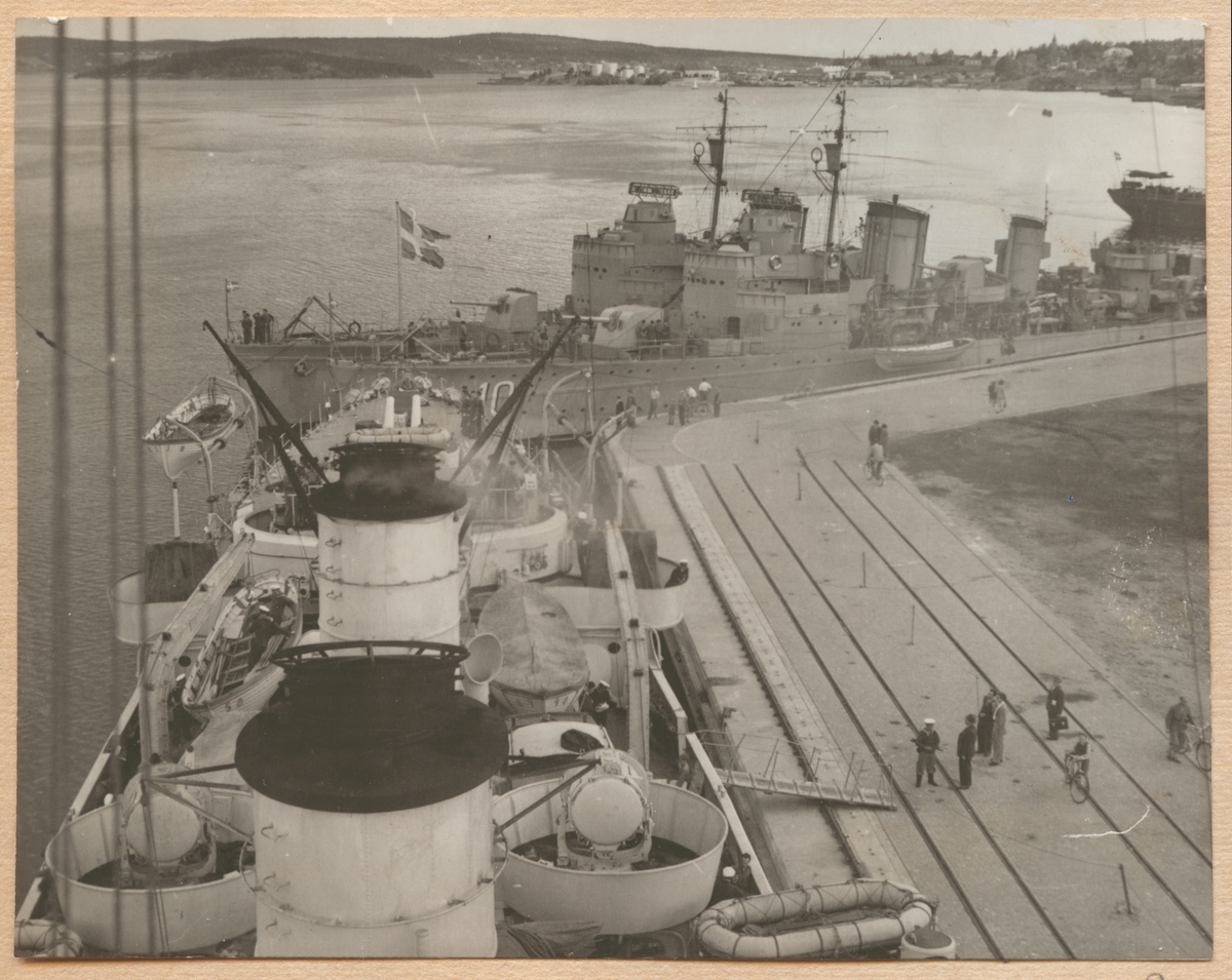 Bilden visar jagaren Norrköping och ett systerfartyg som ligger förtöjt vid kajen i Sundsvall. I förgrunden syns Fylgia. Bilden är tagen från märsen på Fylgia akterut.