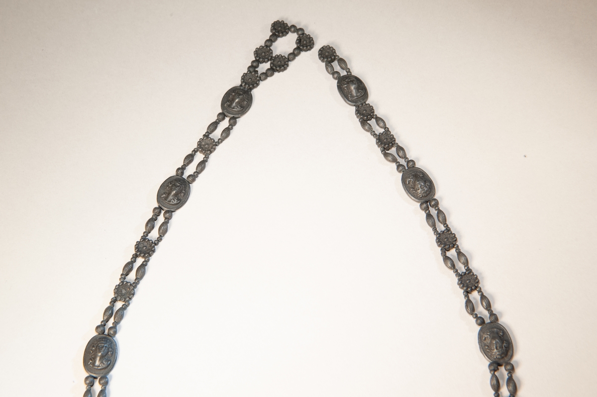 Halsband, bestående av dubbla rader "pärlor" av svart lavasten (?) med ovaler med antika motiv emellan.