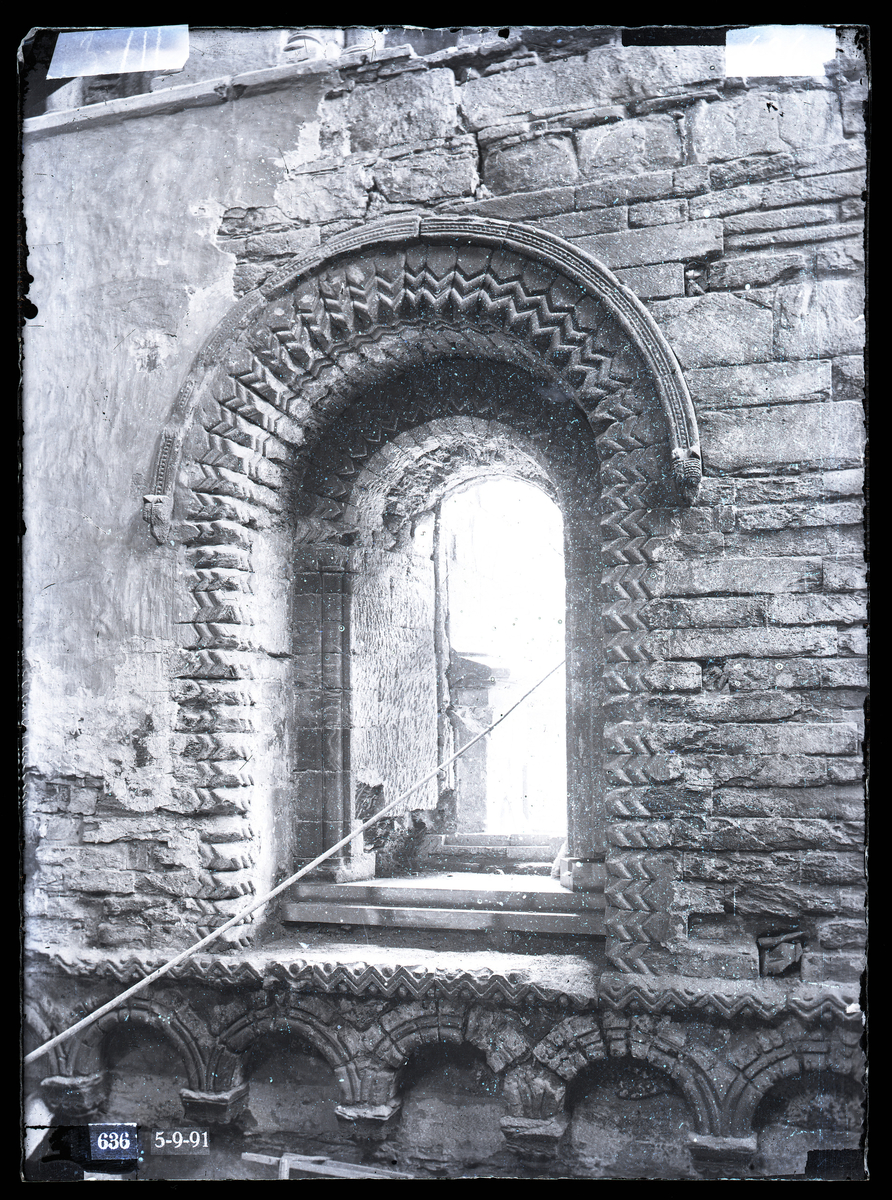 Restaurering av et vindu i vestveggen i nordre tverrskip i Nidarosdomen. Et tau henger gjennom vinduet. Romansk, anglo-normannisk arkitektur med chevroner.