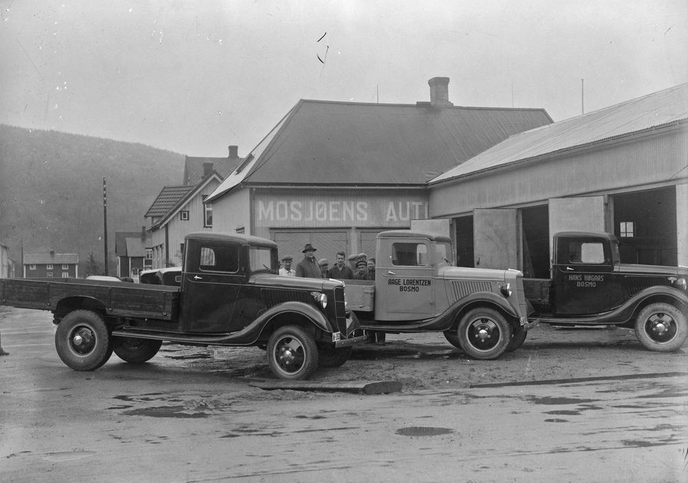 Mosjøen Auto helt sør i C.M. Havigs gate på krysset til Håreks gate.
Tre biler med lasteplan utenfor (Ford V8 1936). 
På døra til den midterste står Aage Lorentzen, Bosmo. 
På døra til den lengst bort står det Hans Høgaas, Bosmo.