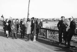 17. mai-tog i Vadsø 1945. Voksne og barn ved et gjerde. Vads