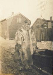 Mann i samisk pesk ved siden av en slede. Ant. i Vadsø. 1917