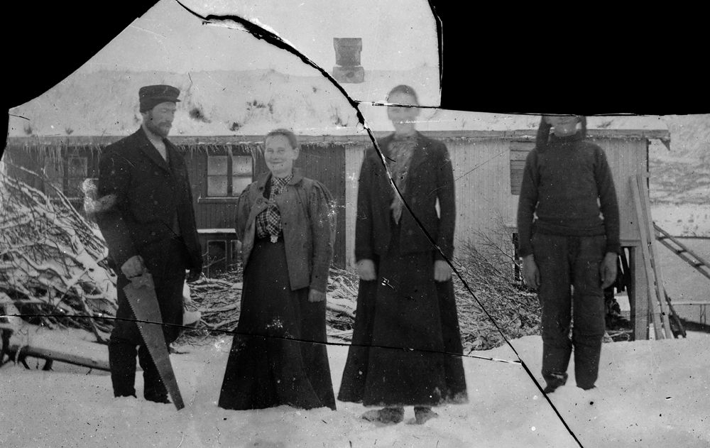Leirfjord. Fire personer foran et hus vinterstid.