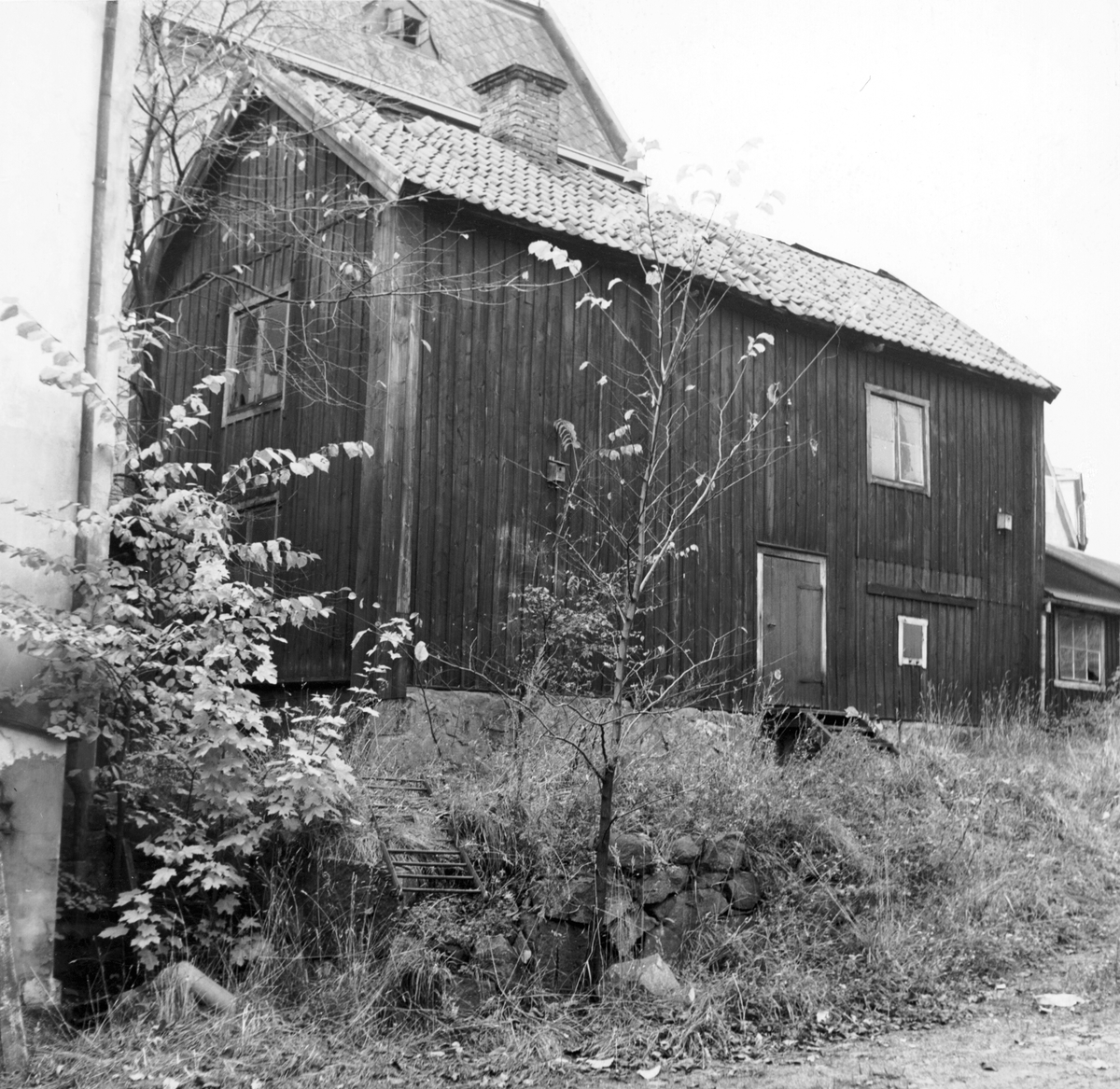 Gårdsinteriör från kvarteret Vårdtornet i Norrköping. I trähuset drev upplysningsvis skräddare Gottfrid Zetterstrand sin verkstad under 1800-talet. Zetterstrand är ett av många exempel på hantverkare som var verksamma i området på 1700- och 1800-talen. Stadsdelen runt kvarteret Vårdtornet har medeltida härkomst och kallades i folkmun Midtina för sitt centrala läge. Bilden är tagen 1957 i samband med rivningsansökan. Vy mot nordväst.