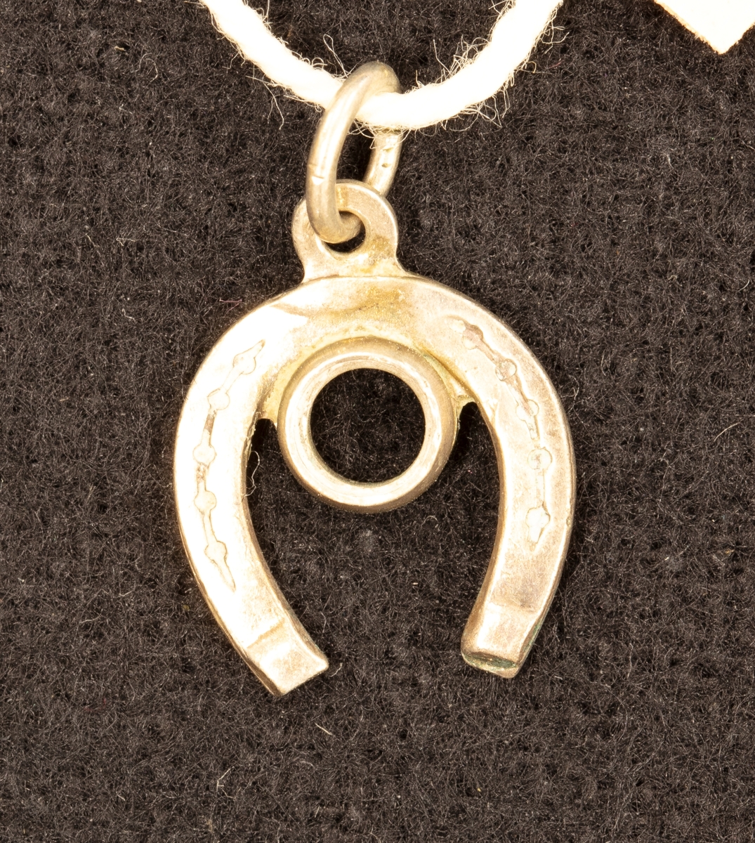 Hängberlock av silver i form av en hästsko med fäste för smyckesten. Diam. 1 cm.

Ingår i en samling smycken som givaren köpt på auktion eller hos antikhandlare.