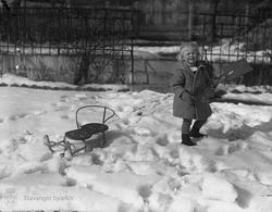 Jente med kjelke og spade i snøen