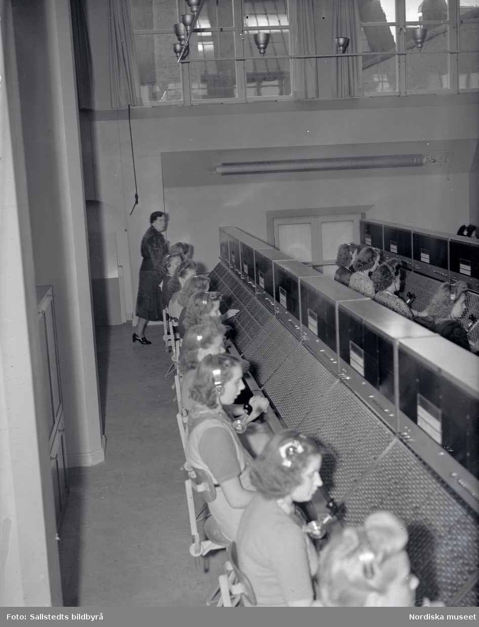 Telefonister på Stockholms telefonstation år 1946. En rad med kvinnor sitter vid ett växelbord och kopplar samtal.