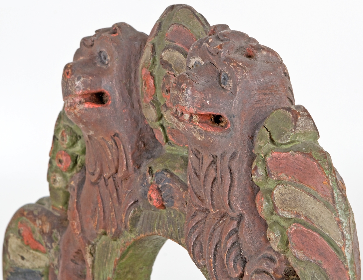 Selkrok av trä, skulpterad och målad i grönt, brunt, rött, svart och vitt. Skulpteringen föreställer två stycken lejon.
Rokoko.
