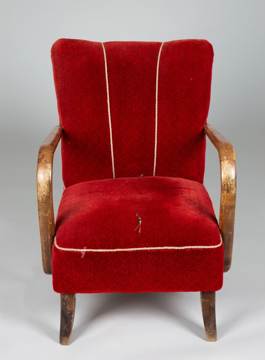 Lenestol, stuemøbel
Stolen er fabrikkprodusert antatt på 1950-tallet. Tidstypisk modell.
Lakkerte leiner, der lakken er for det meste løsnet.
Stoff i rødt ull/velur med kvite pyntelisser.
Setet er noe slitt med en revne i forkant.