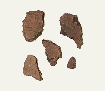 Ett antal fragment av grovmagrad keramik. Påträffat tillsammans med pärlor av bergkristall och karneol.