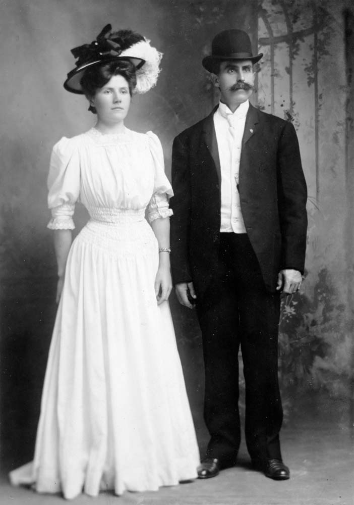 Portrett av mann og kvinne i pene klær og hatter.
