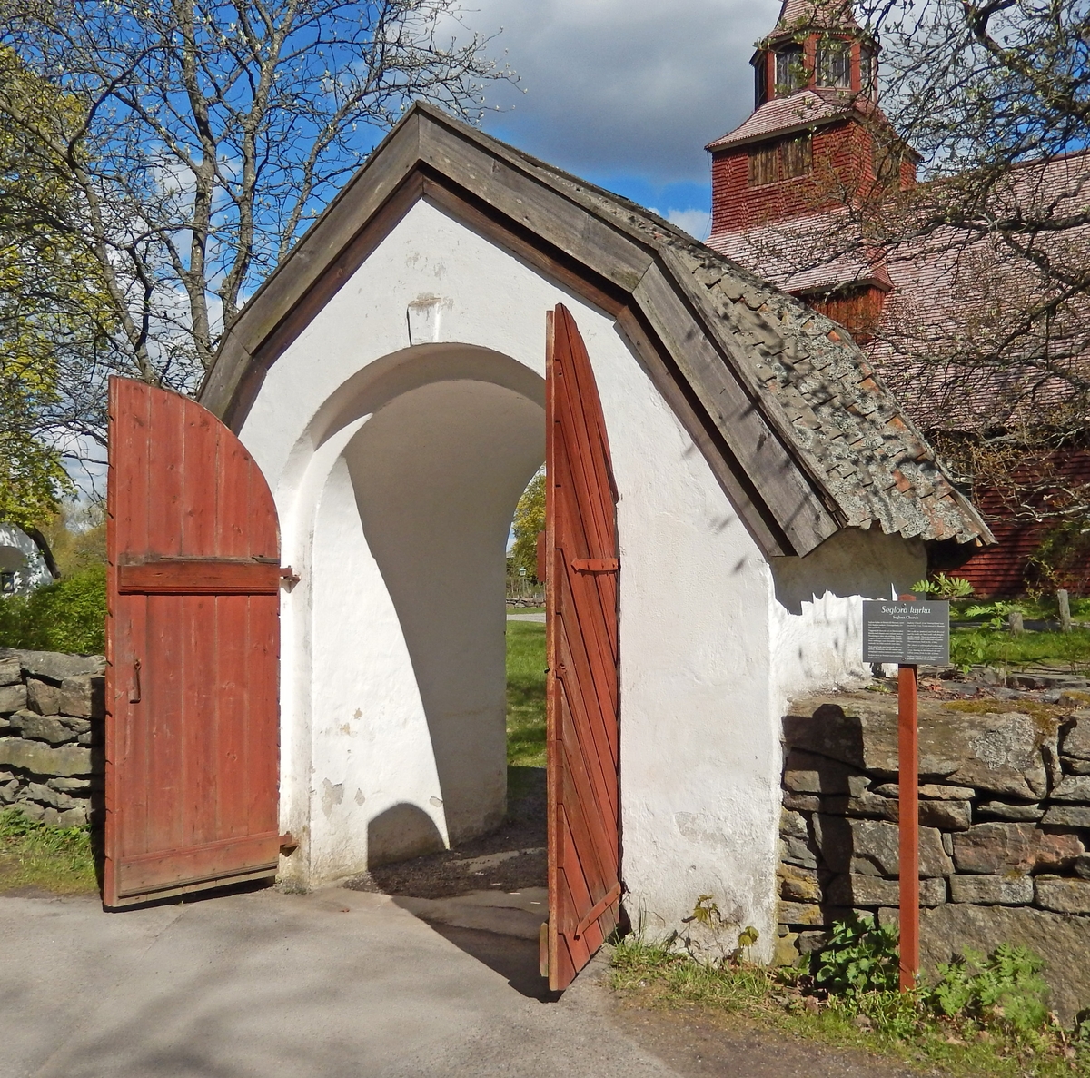 Den södra stigluckan, kyrkogårdsporten, vid Seglora kyrka på Skansen är murad, putsad och vitkalkad. Taket är brutet och klätt med enkupigt tegel. Portdörrarna är av trä, rödmålade, med stående panel på insidan samt fiskbenspanel på utsidan. Södra stigluckan på Skansen är uppförd som en kopia av den södra stigluckan "Prästgårdsporten" vid Seglora kyrka i Västergötland.