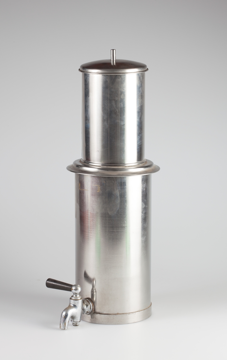 Filterpresse i rustfritt stål. Består av fire deler: Sylinder med tappekran (A). konisk filter (B), lokk (C) og stempel (D).