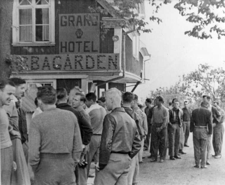 En större grupp män samlade utanför Ribbagården. Skylt på väggen som säger bland annat: "Grand Hotel Ribbagården".