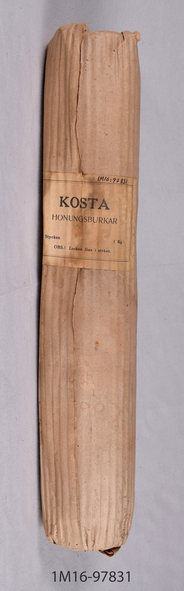Förpackning av grått papper, innehållande två honungsburkar av glas, med plåtlock. Från Clarence Janssons handel, Ö Sörby, Borgholm, som drevs 1933-1971.