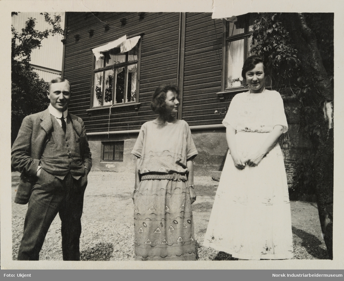 En mann og to kvinner står på gårdsplass foran bolighus i Skottland