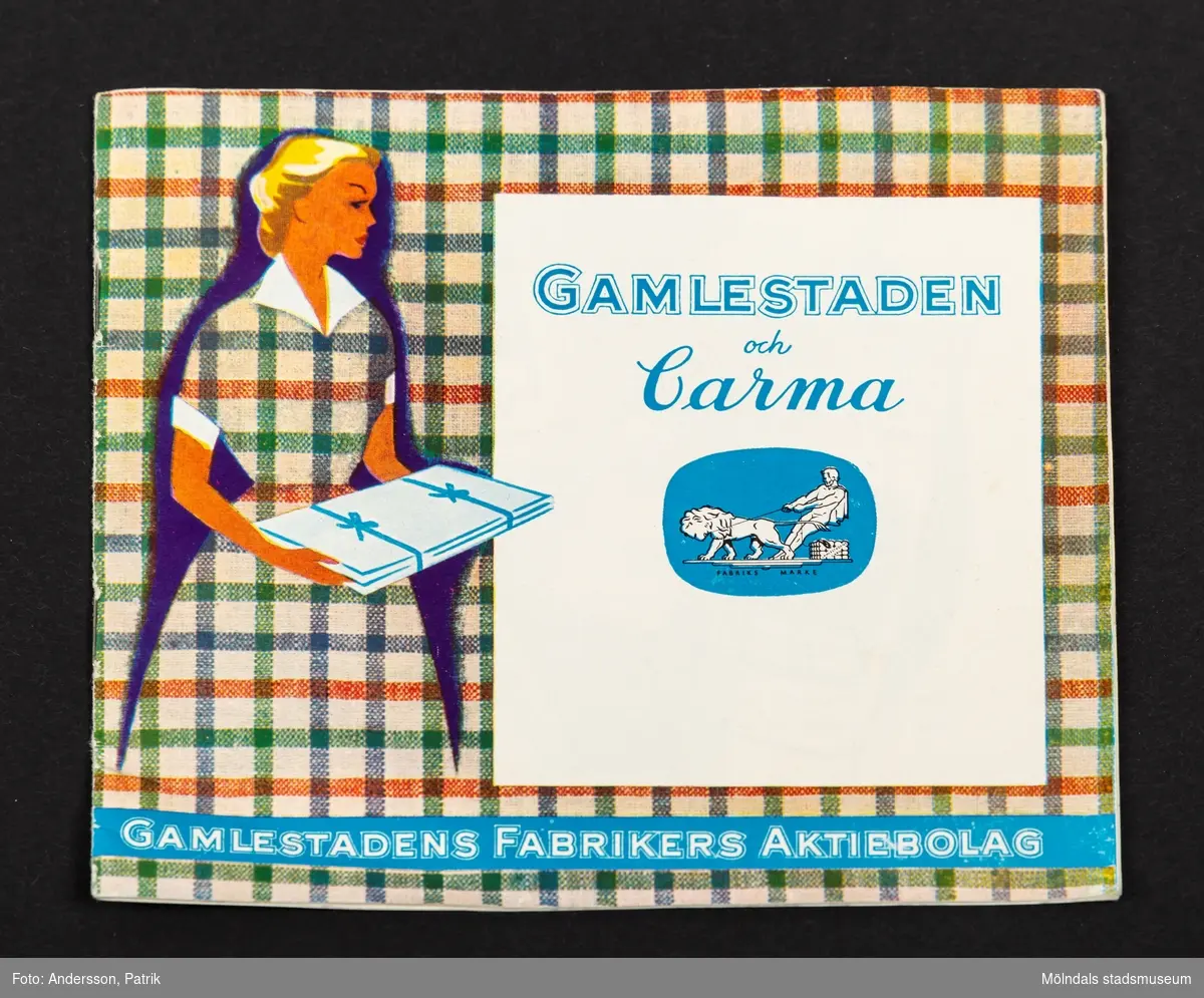 Produkt och mönsterhäfte från Gamlestadens fabrikers aktiebolag med titeln Gamlestaden och Carma (reklamhäfte). På framsidan syns en kvinna med en klänning i rutigt tyg som är likadant som bakgrunden. Titeln står i en vit kvadrat.
