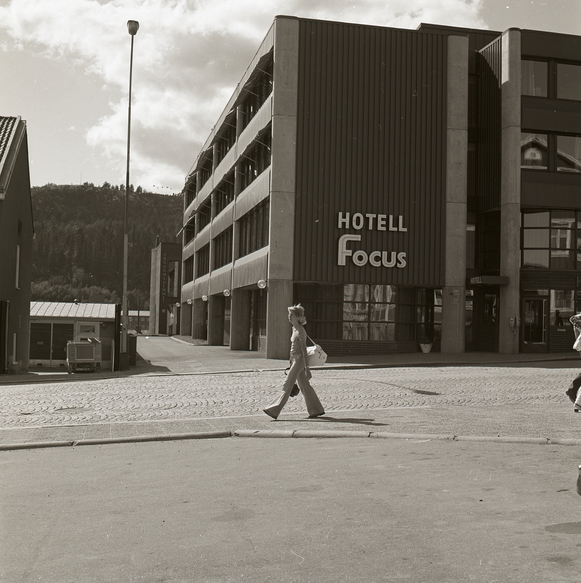 En kvinna med handväska promenerar förbi Hotell Focus i Örnsköldsvik, 19 juli 1974.