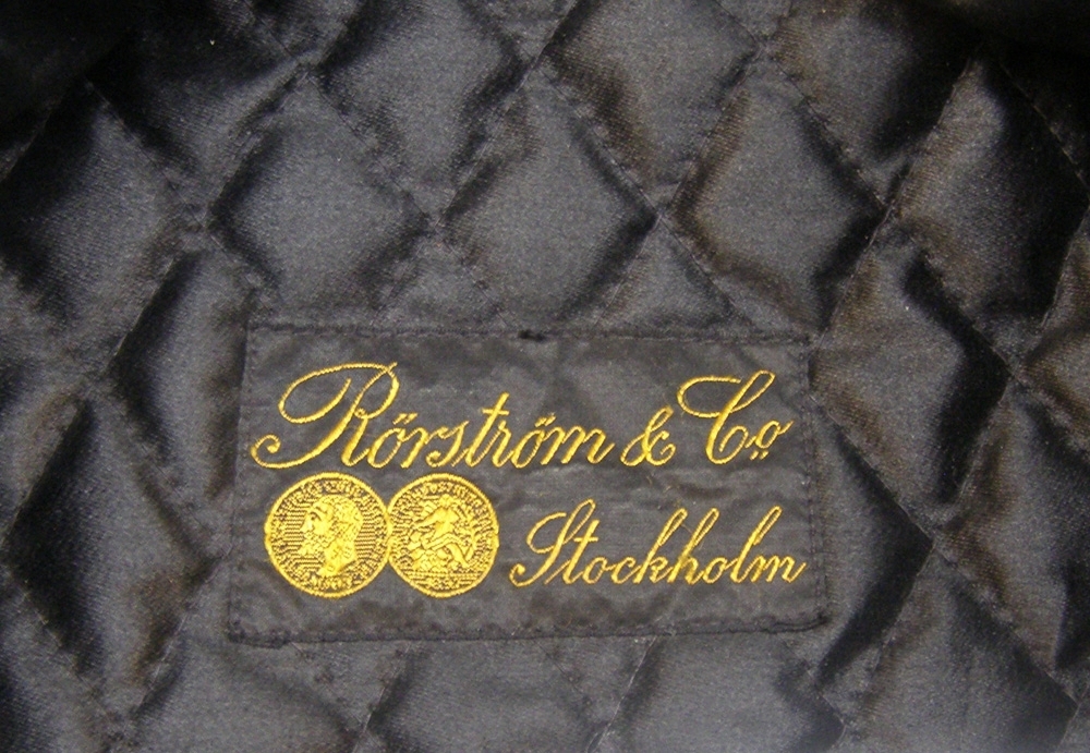Skärmmössa av mörkblått kläde med 3 x 3 mm guldfärgad galon, svart kulträns och nationalkokard av metall.